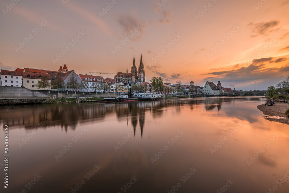Regensburg during sunset with Danube river and cathedral and stone bridge at golden hour, Germany