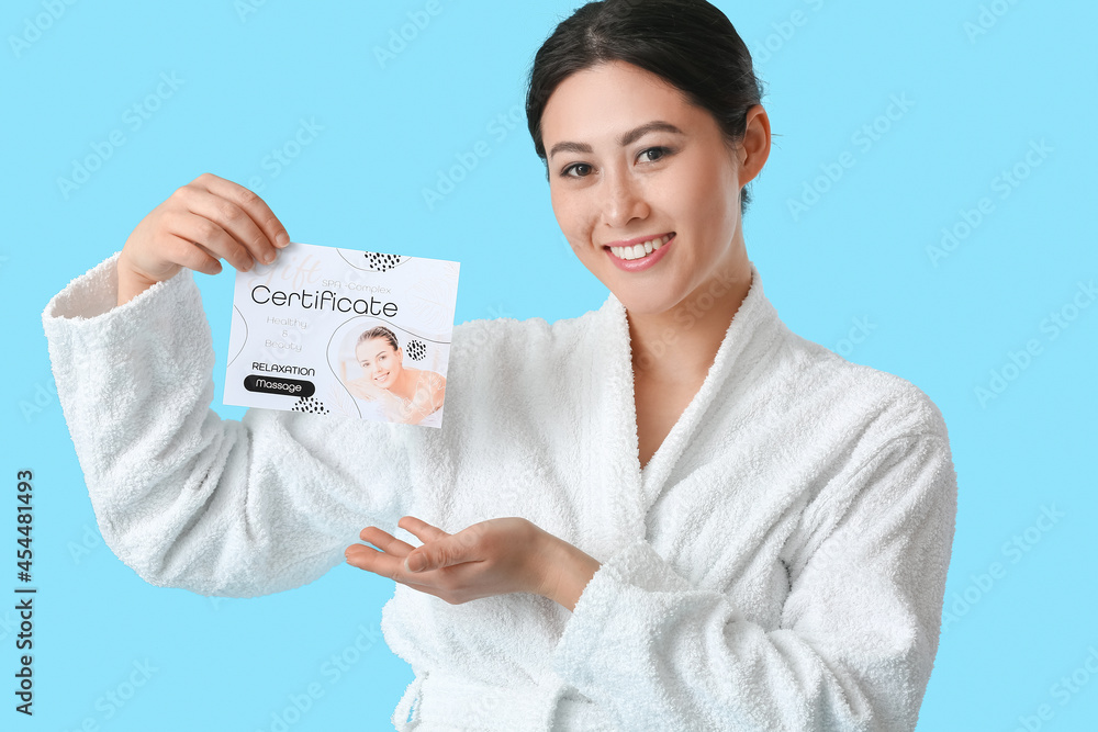 Young Asian woman with gift certificate for massage on color background Young Asian woman with gift certificate for massage on color background