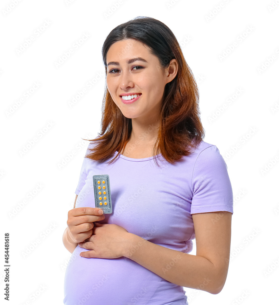 Young pregnant Asian woman with pills on white background Young pregnant Asian woman with pills on white background