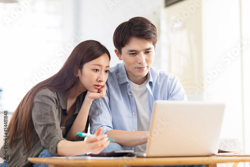 Young couple planning budget,looking at laptop screen, checking finances.