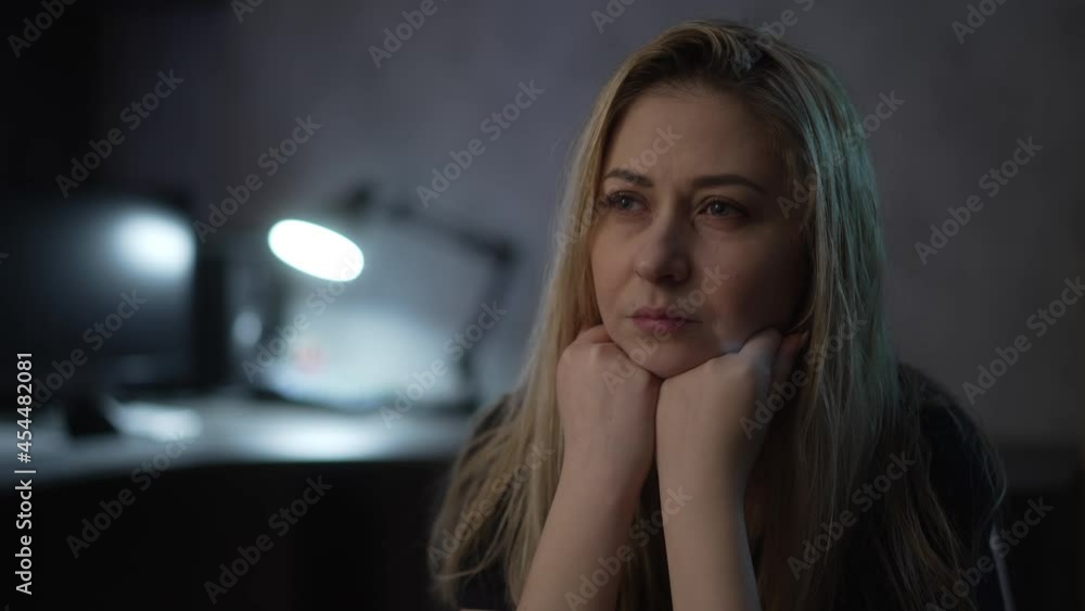 Unhappy blonde lady with messy hair suffers from depression and bad thoughts in semi-dark room with glowing lamp at home extreme close view slow motion Unhappy blonde lady with messy hair suffers from depression and bad thoughts in semi-dark room with glowing lamp at home extreme close view slow motion
