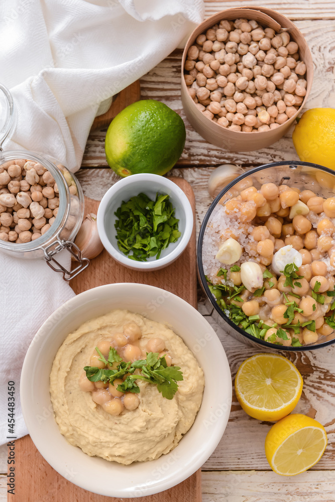 Composition with tasty hummus and ingredients on light wooden background