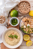 Composition with tasty hummus and ingredients on light wooden background