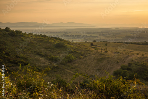 Golden sunrise in the mountains. Dawn in the mountains. The sun rises from behind the mountains. Beautiful green hills and green valley. Little sleeping town. Mountains in the fog. Carpathian, Ukraine