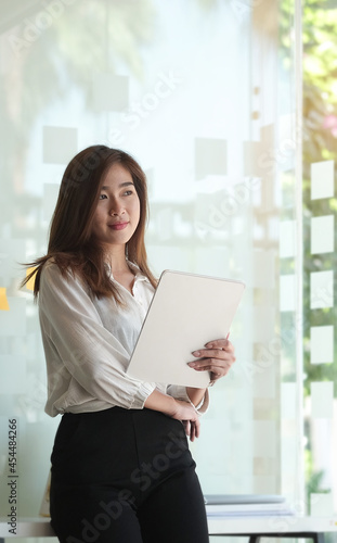 Portrait of businesswoman holding digital tablet and standing in modern office. Free Download Portrait of businesswoman holding digital tablet and standing in modern office. - GFXLoad