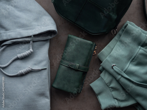 Tracksuit, green purse and bag on a gray background. Women's, modern youth clothing.
