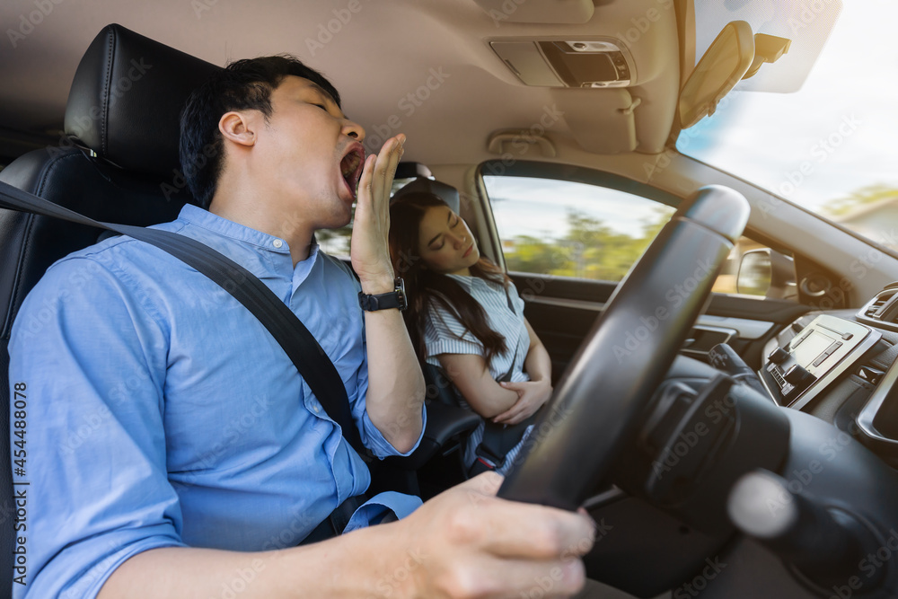 Obraz premium sleepy man yawning while driving car and his wife is sleeping