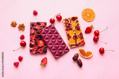 Handmade chocolate bars with fruits, berries and nuts on color background