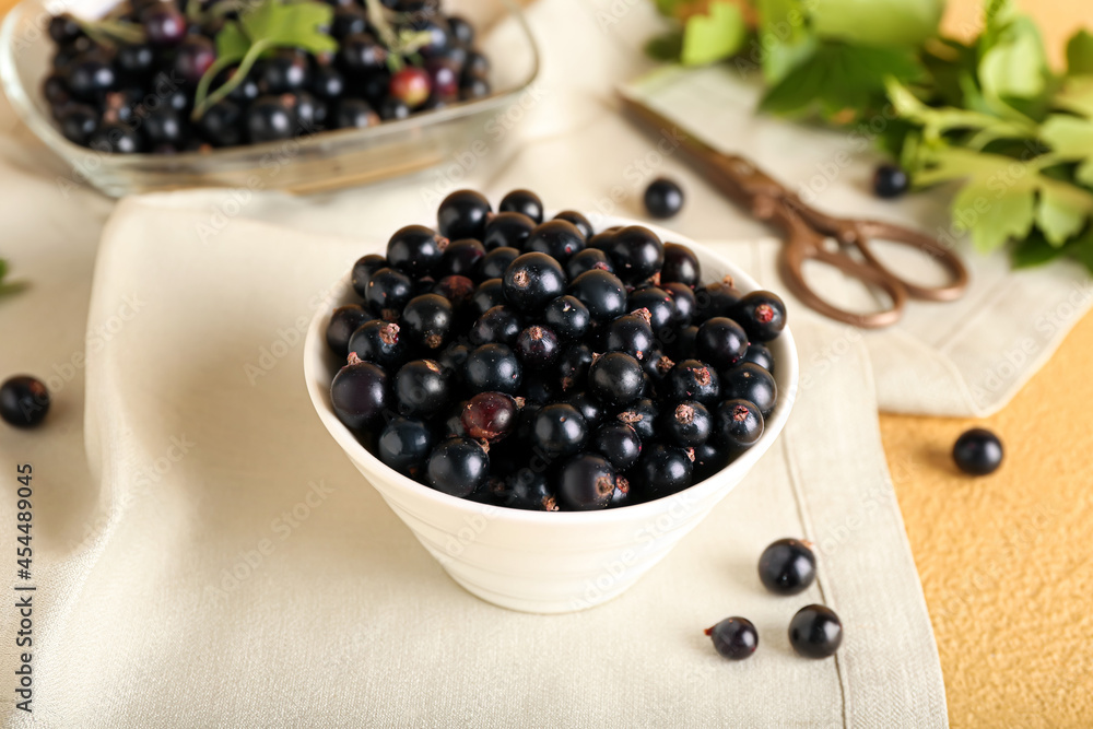 Bowl with ripe black currant on color background Bowl with ripe black currant on color background