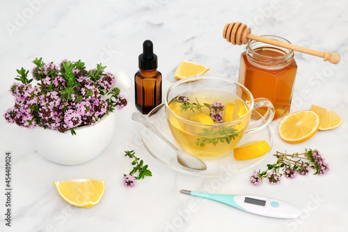Natural herbal plant medicine for flu and cold virus with thyme herb, honey, lemon, thermometer and essential oil bottle. Immune system boosting medication, is anti bacterial, antiseptic, anti viral.