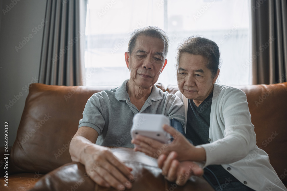 Asian senior couple checking blood pressure at home, they're staring the blood pressure gauge waiting the result. Asian senior couple checking blood pressure at home, they're staring the blood pressure gauge waiting the result.