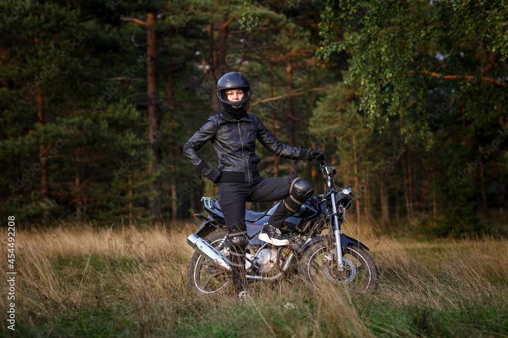 biker girl in black clothes and black helmet on a motorcycle