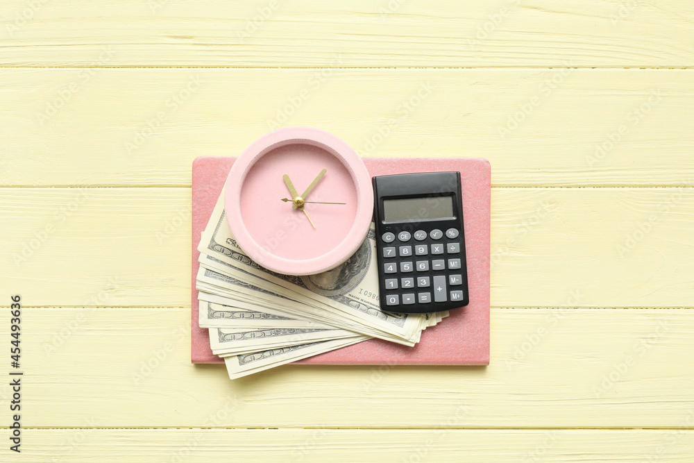 Alarm clock with money and notebook on color wooden background Alarm clock with money and notebook on color wooden background