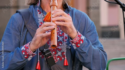 wooden flute. close-up. embroidered shirt. Street musician, in an embroidered shirt, plays on sopilka, wooden flute, musical woodwind instrument. sopilka. Vyshyvanka. photo