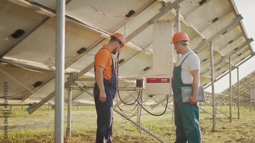 Workers installing PV Photovoltaic, solar panels, which converts solar energy into electric energy. Connecting and configuring solar panels to the network. Concept of green energy.