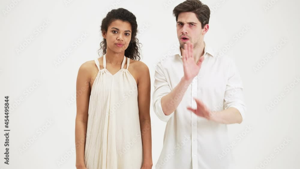 Serious couple man and woman giving negative answer standing isolated over white background in the studio Serious couple man and woman giving negative answer standing isolated over white background in the studio