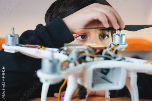 The boy diligently puts the propeller on the drone. Extracurricular physics work in the home lab. Innovative education