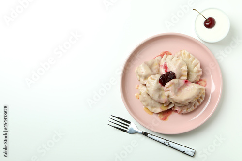 Plate with pierogi with cherry on white background