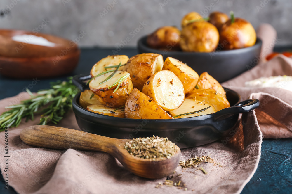 Frying pan with baked potatoes and rosemary on dark background Frying pan with baked potatoes and rosemary on dark background