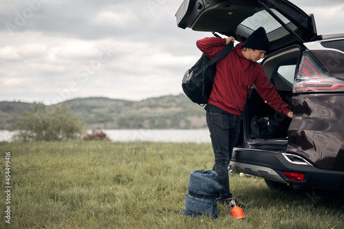 Camper packing and unpacking from a car's back door in nature.