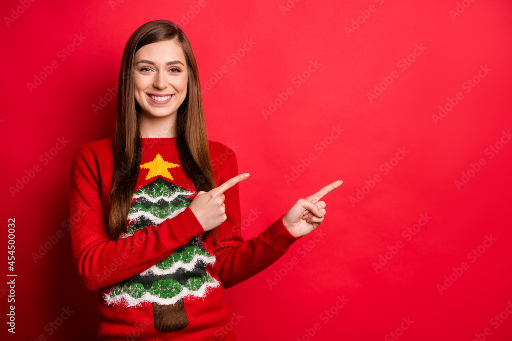 Photo of cute millennial lady point empty space wear holiday sweater isolated on red color background Photo of cute millennial lady point empty space wear holiday sweater isolated on red color background