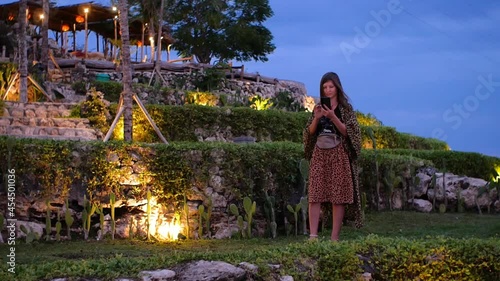 Woman chatting vis smartphone on tropical island on sunset in Bali Indonesia. High quality FullHD footage photo