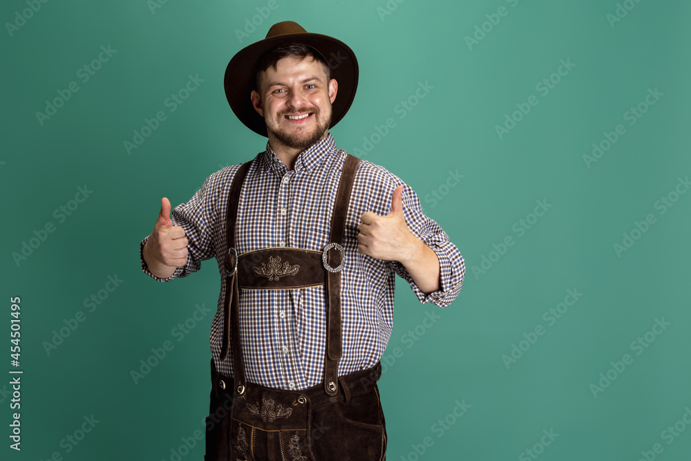 Portrait of bearded smiling man in traditional Bavarian costume standing alone isolated over green background. Octoberfest, Festival concept Portrait of bearded smiling man in traditional Bavarian costume standing alone isolated over green background. Octoberfest, Festival concept