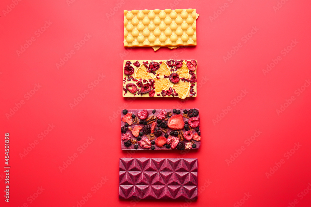 Obraz premium Handmade chocolate bars with fruits, berries and nuts on color background