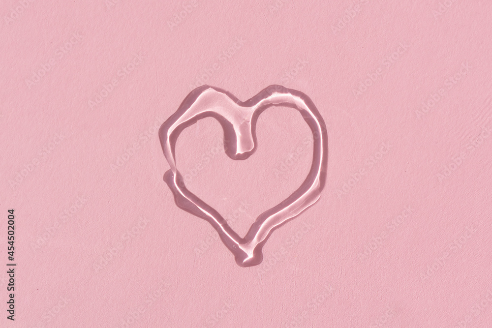 pouring face serum in a shape of a heart on a pink background