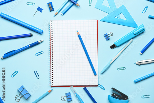 Blank notebook and set of stationery on color background