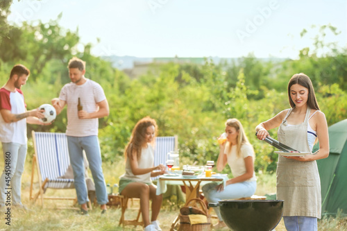 Young woman cooking food on barbecue grill outdoors