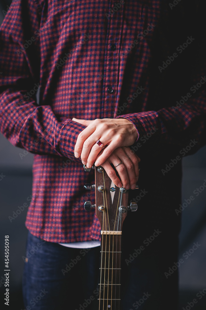 Guitarist holding two hands with an acoustic guitar