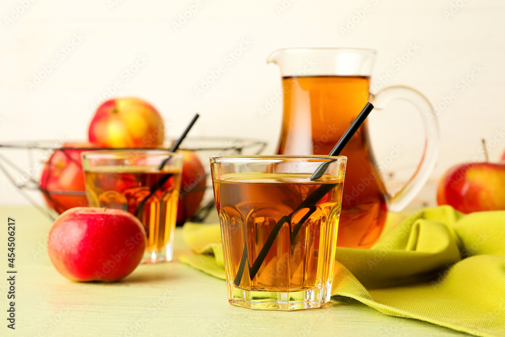 Jug and glasses of tasty apple juice on color wooden table Jug and glasses of tasty apple juice on color wooden table