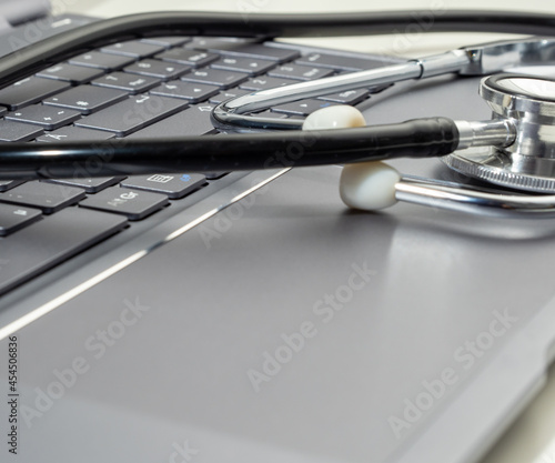 Stethoscope lies on laptop keyboard. 