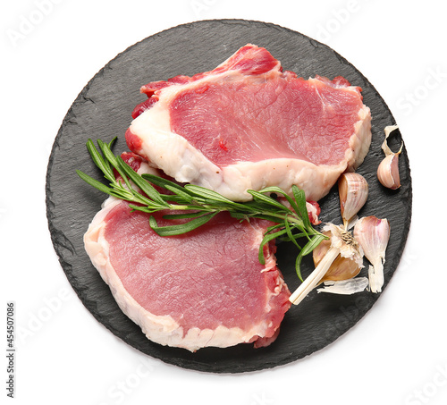 Board with raw pork steaks and rosemary on white background