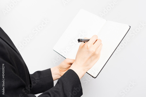 ノートにメモを書く女性の手元