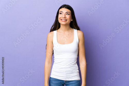 Young brunette woman over isolated purple background thinking an idea while looking up