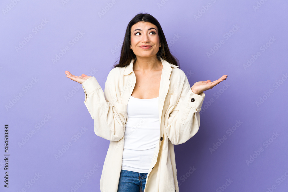 Young brunette woman over isolated purple background having doubts while raising hands Young brunette woman over isolated purple background having doubts while raising hands