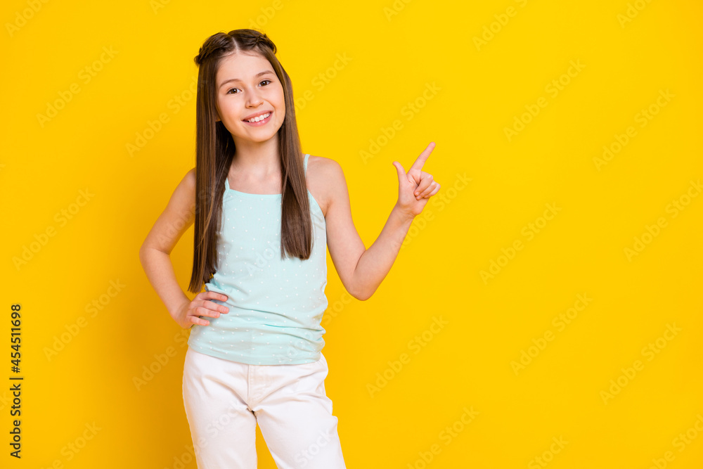 Photo of cheerful nice positive little lady point finger empty space sale news isolated on yellow color background Photo of cheerful nice positive little lady point finger empty space sale news isolated on yellow color background
