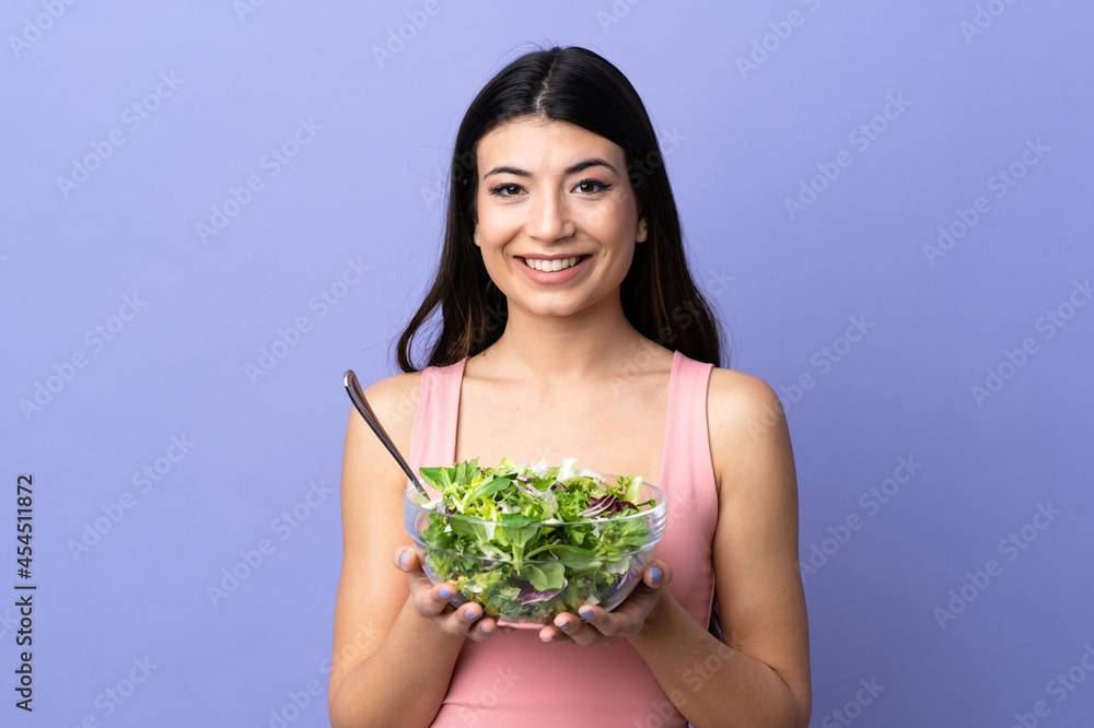 Young woman with salad over isolated purple background Young woman with salad over isolated purple background