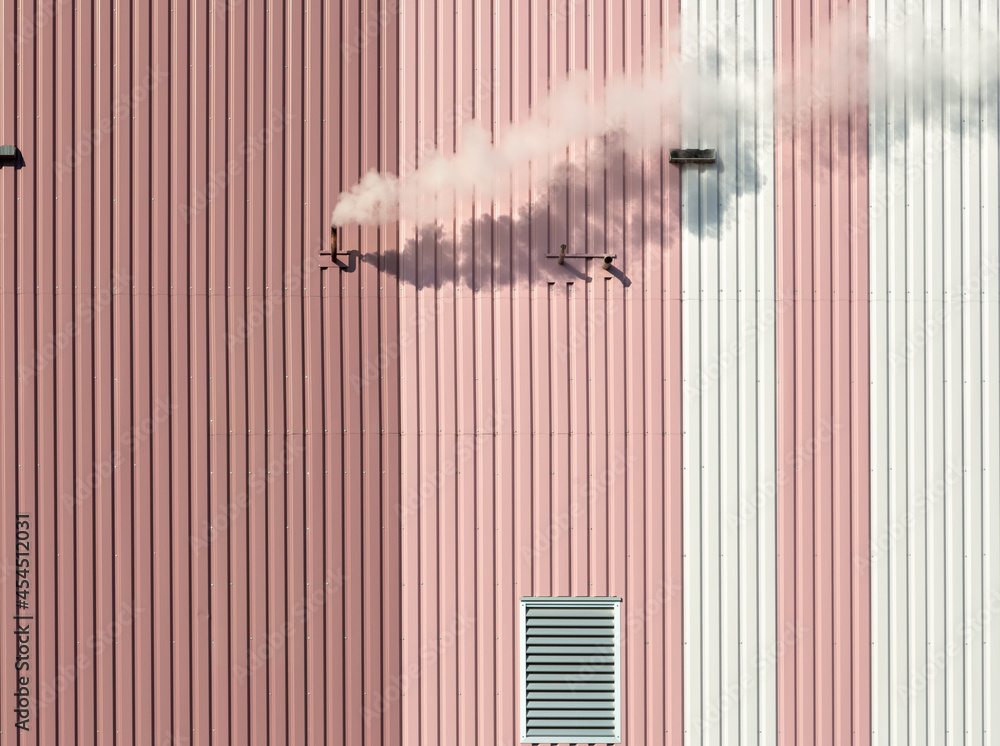 Cloud of smoke coming out of a pipe on a pink and white building - obrazy, fototapety, plakaty 