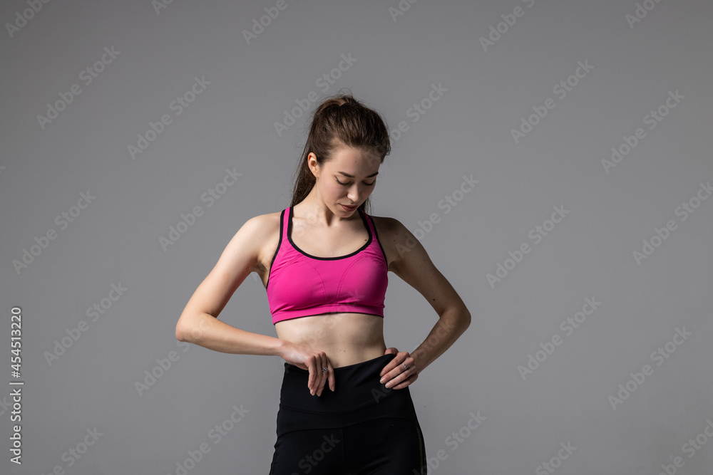 Happy beautiful fit woman after gym exercise isolated on grey background. Carefree fitness girl resting. Happy beautiful fit woman after gym exercise isolated on grey background. Carefree fitness girl resting.