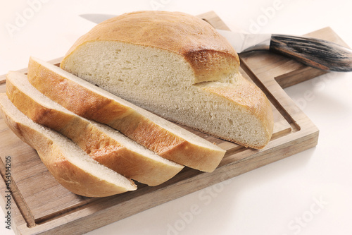 round bread cut into slices on a wooden board with a knife