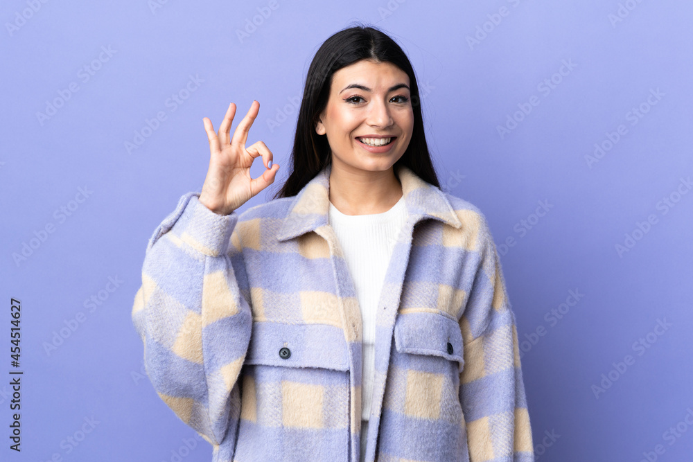 Young brunette woman over isolated purple background showing ok sign with fingers Young brunette woman over isolated purple background showing ok sign with fingers