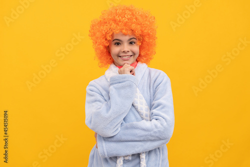 cheerful child in fancy orange wig hair wear home bathrobe, morning