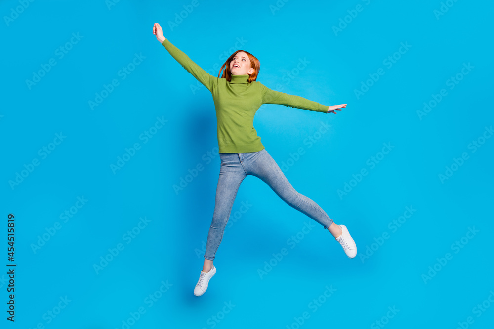 Full length photo of carefree cheerful lady raise hand fist look empty space flying isolated on blue color background