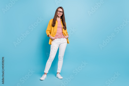 Full body photo of young attractive woman happy positive smile hands in pocket isolated over blue color background