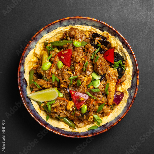 Udon stir-fry noodles bowl and vegetables on black stone background. Asian cuisine. Top view. Copy space.
