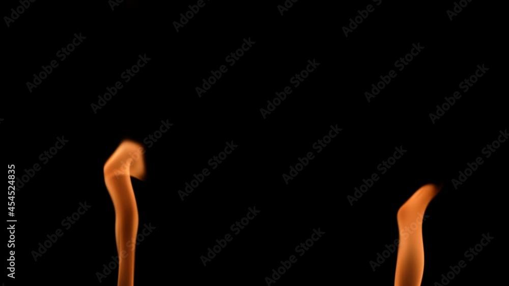 Two high flame ignite and glow with orange yellow fire against a black background. A real bonfire, burner or torch flares up in the dark. Fire glow, dangerous blazing fire close up. Slow motion. Two high flame ignite and glow with orange yellow fire against a black background. A real bonfire, burner or torch flares up in the dark. Fire glow, dangerous blazing fire close up. Slow motion.