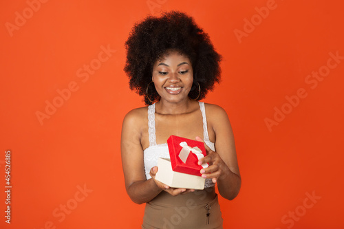 joyful young african female opens a gift at the holiday 